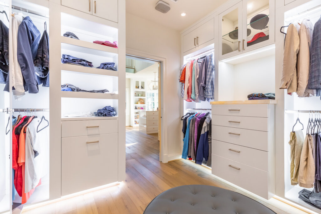 Custom closet design featuring integrated lighting, open shelving, hanging space, and drawer cabinets for organized storage