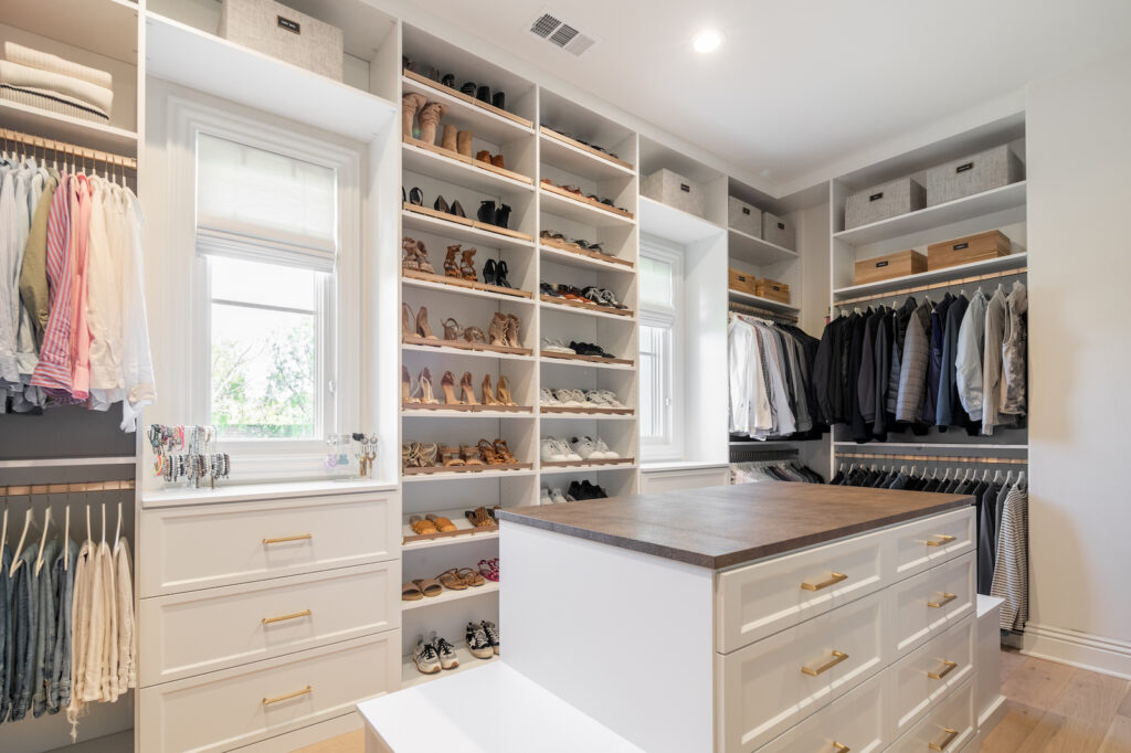 Custom walk-in closet with built-in shoe shelving, hanging sections, and a center island with drawer storage