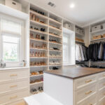 Custom walk-in closet with built-in shoe shelving, hanging sections, and a center island with drawer storage