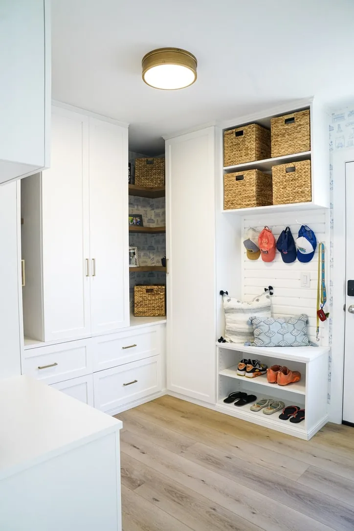 White entry storage with baskets, wall hooks and open shelves for shoes